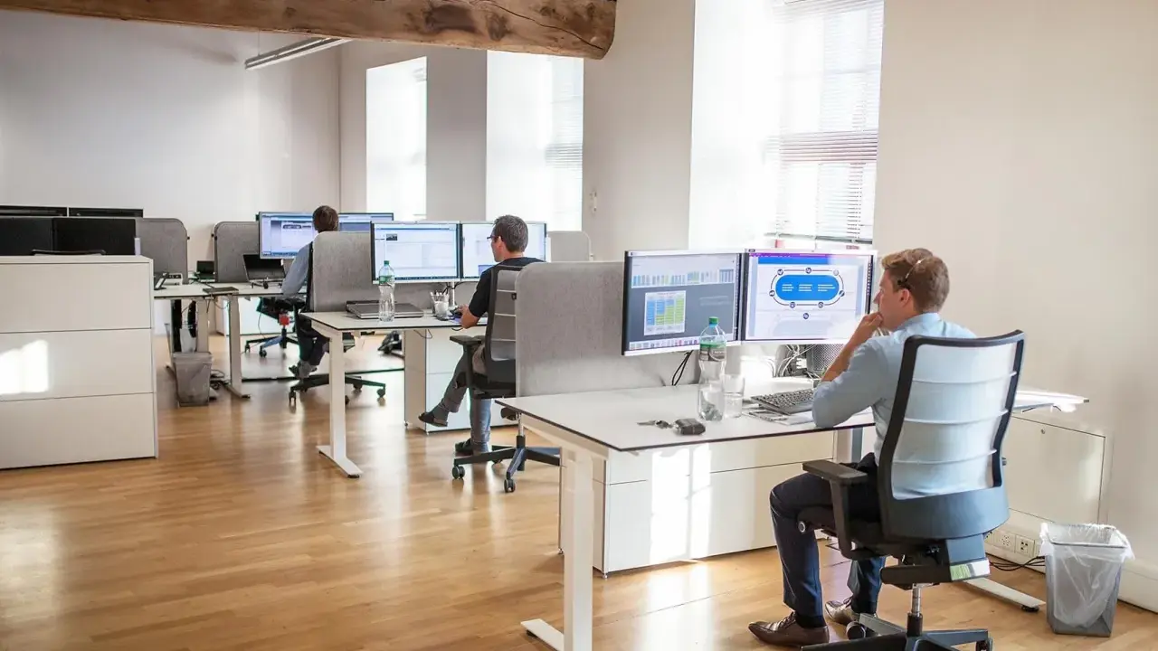 Bureau moderne avec employés travaillant sur des ordinateurs. Un homme utilise un service de bureau cloud pour gérer des données.