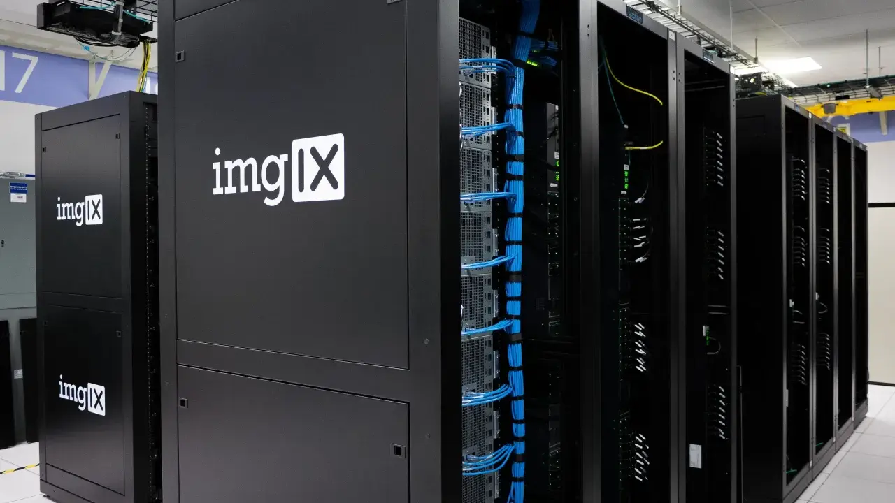 Des racks de serveurs noirs, dont un avec le logo "imgIX", remplis de câbles bleus et jaunes. C'est un peu ça, un serveur : le cœur de l'internet.