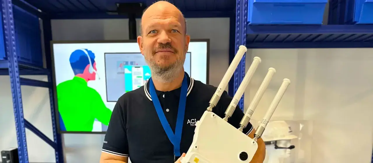 Un homme souriant tient un appareil avec quatre antennes, prêt à optimiser votre reseau wifi.
