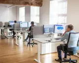 Bureau moderne avec employés travaillant sur des ordinateurs. Un homme utilise un service de bureau cloud pour gérer des données.