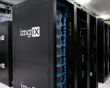 Des racks de serveurs noirs, dont un avec le logo "imgIX", remplis de câbles bleus et jaunes. C'est un peu ça, un serveur : le cœur de l'internet.
