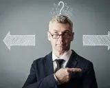 Un homme d'affaires réfléchit, entouré de points d'interrogation et de flèches. Il cherche la meilleure solution, peut-être avec un logiciel GED.