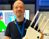 Un homme souriant tient un appareil avec quatre antennes, prêt à optimiser votre reseau wifi.