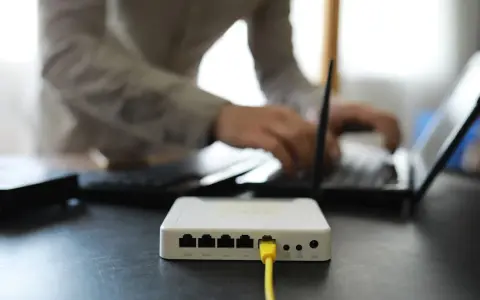Connexion internet : faut il mettre les espaces pour la clé wifi ? Un routeur blanc est branché, une personne tape sur un ordinateur portable.