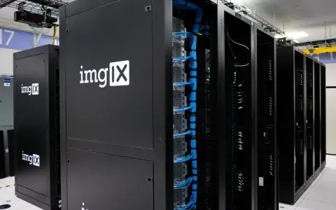 Des racks de serveurs noirs, dont un avec le logo "imgIX", remplis de câbles bleus et jaunes. C'est un peu ça, un serveur : le cœur de l'internet.