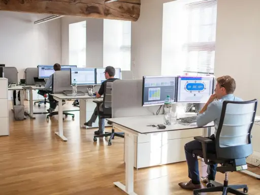 Bureau moderne avec employés travaillant sur des ordinateurs. Un homme utilise un service de bureau cloud pour gérer des données.