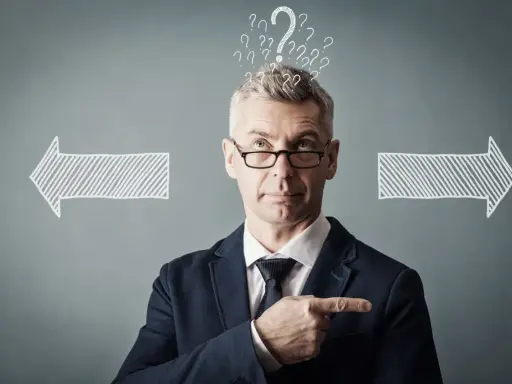 Un homme d'affaires réfléchit, entouré de points d'interrogation et de flèches. Il cherche la meilleure solution, peut-être avec un logiciel GED.