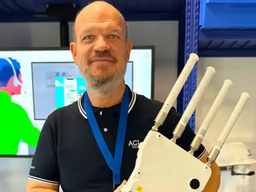 Un homme souriant tient un appareil avec quatre antennes, prêt à optimiser votre reseau wifi.