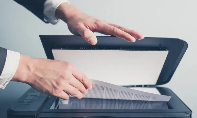 Un homme en costume utilise un scanner ged pour numériser un document important.
