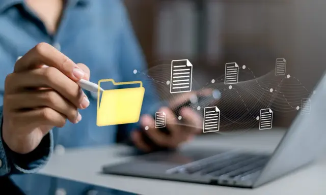 Main d'une personne utilisant un stylet pour interagir avec une icône de dossier jaune, symbolisant la digitalisation des processus et le flux de documents numériques.