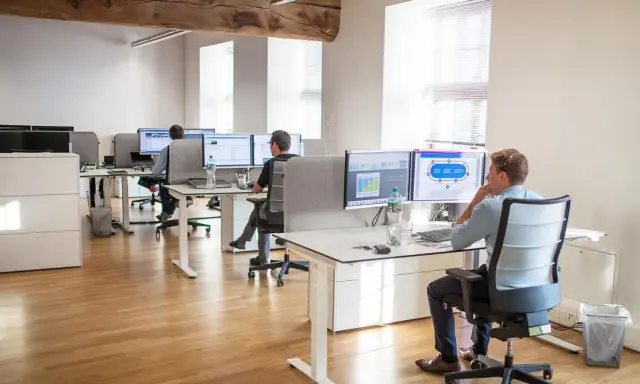 Bureau moderne avec employés travaillant sur des ordinateurs. Un homme utilise un service de bureau cloud pour gérer des données.
