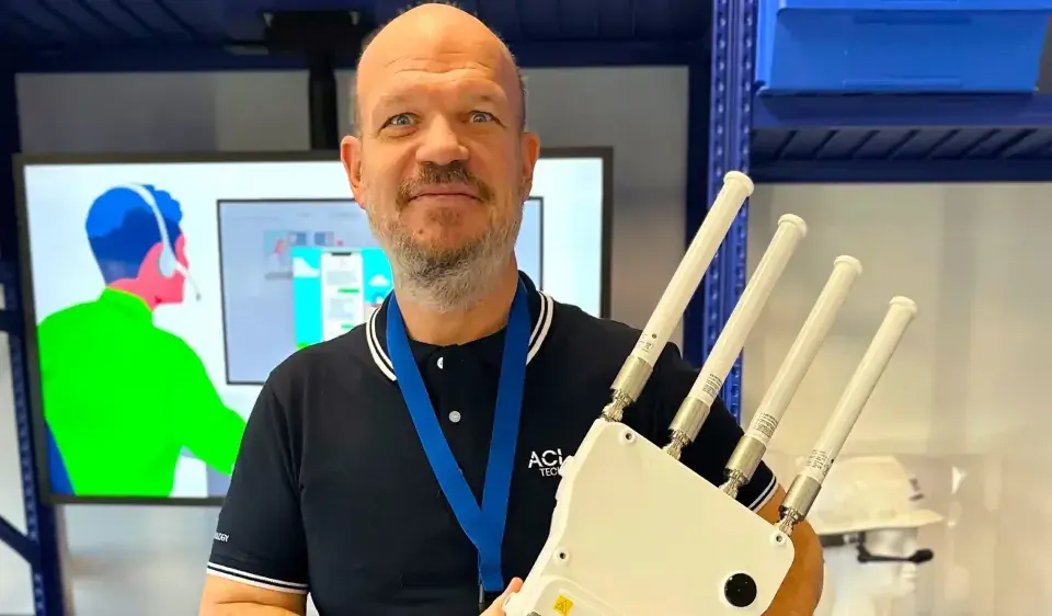 Un homme souriant tient un appareil avec quatre antennes, prêt à optimiser votre reseau wifi.
