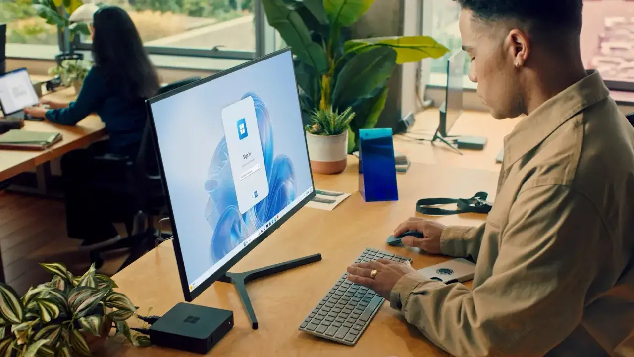 Un homme utilise un ordinateur avec un écran affichant une connexion Windows, suggérant l'accès à des services Windows VM online.